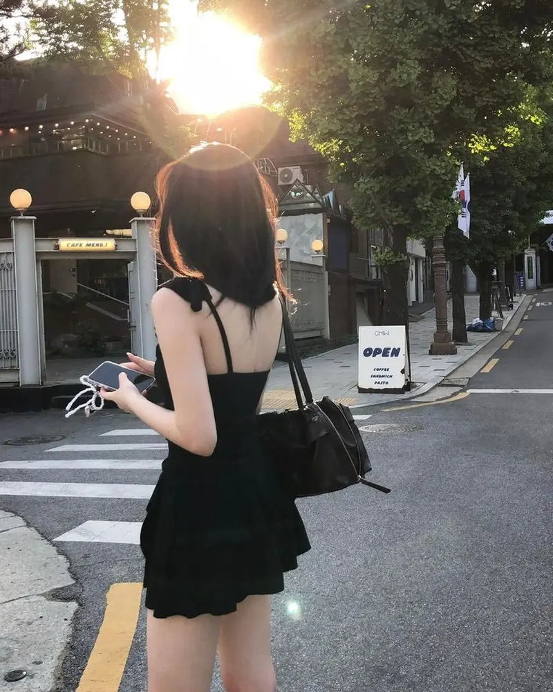 Cô gái trong bộ váy đen ngắn quay lưng lại dưới ánh mặt trời Cô gái trong bộ váy đen ngắn quay lưng lại dưới ánh mặt trời