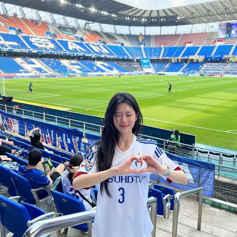 Gái xinh mặc áo bóng đá Adidas màu trắng, nổi bật trên sân khán đài ngoài trời Gái xinh mặc áo bóng đá Adidas màu trắng, nổi bật trên sân khán đài ngoài trời