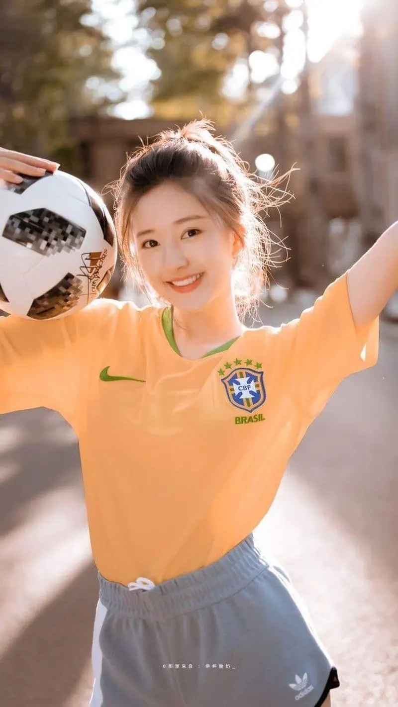 Gái xinh mặc áo bóng đá màu cam tạo dáng bên quả bóng cổ vũ bóng đá cực chất Gái xinh mặc áo bóng đá màu cam tạo dáng bên quả bóng cổ vũ bóng đá cực chất