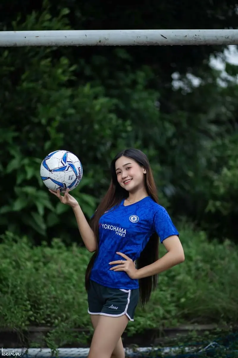 Hình ảnh cô gái trẻ năng động chơi bóng với áo bóng đá màu xanh đậm tại sân cỏ. Hình ảnh cô gái trẻ năng động chơi bóng với áo bóng đá màu xanh đậm tại sân cỏ.