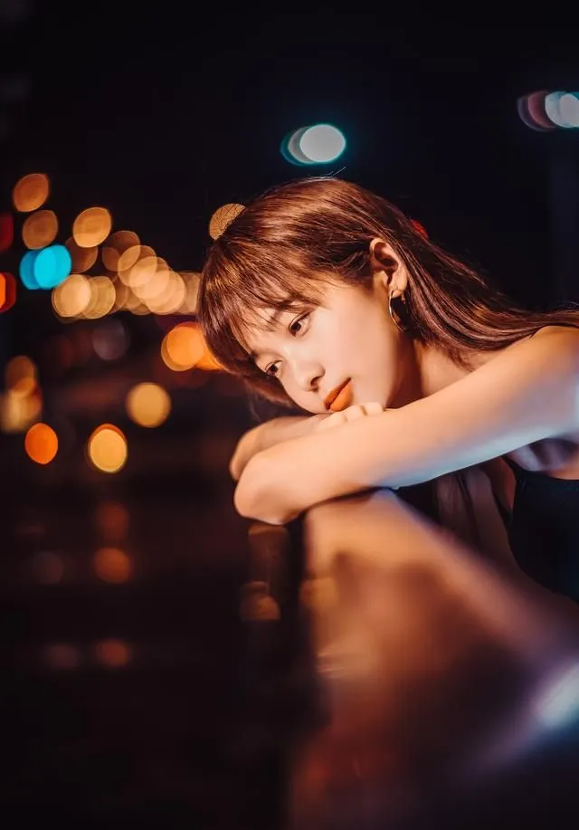 Ánh đèn mờ ảo phản chiếu gương mặt cô đơn buồn tủi của cô gái trẻ. Ánh đèn mờ ảo phản chiếu gương mặt cô đơn buồn tủi của cô gái trẻ.